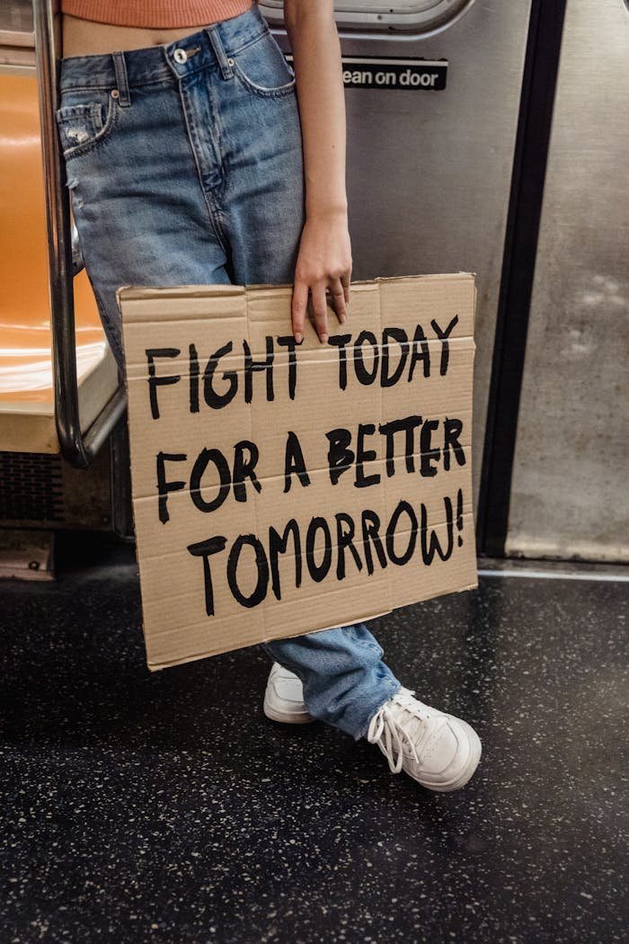 Mastering the First Impression: Your intriguing post title goes here A person holding a protest sign in a subway advocating for a better future.